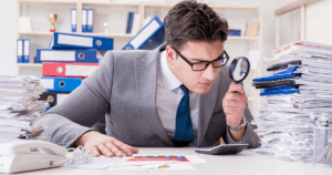 Conciliación bancaria: contador comparando estados de cuenta bancarios con registros contables en computadora